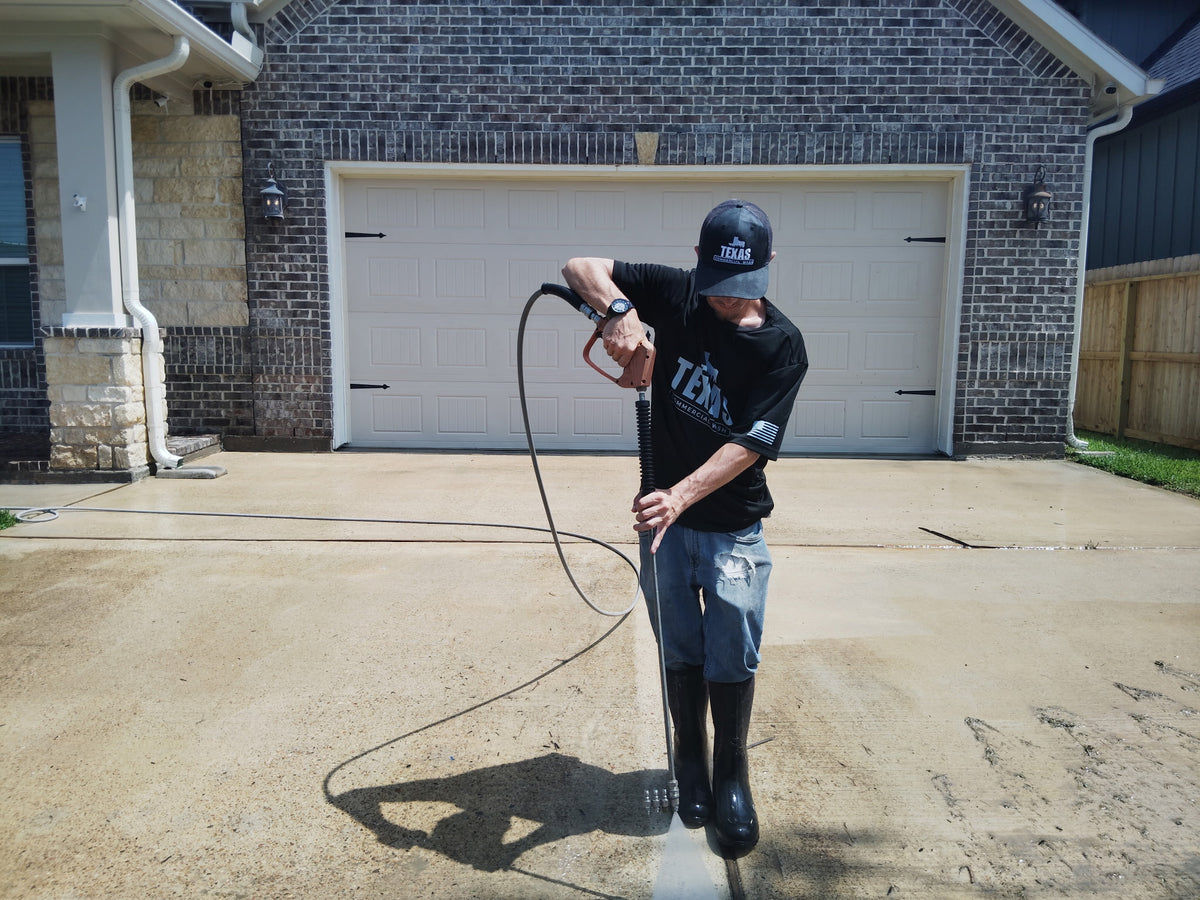 Technician pressure washing a residential driveway